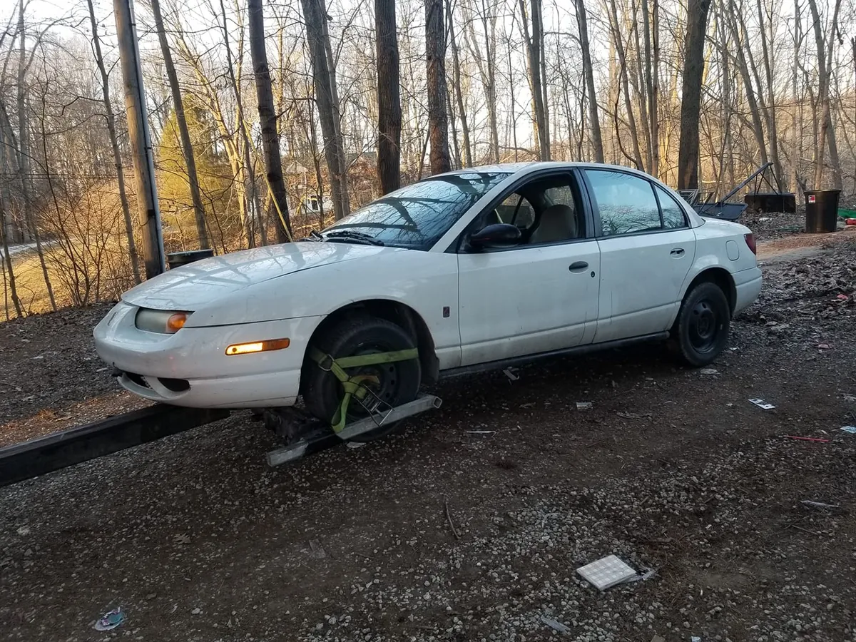 Non-running Saturn sedan strapped to a tow dolly in Indianapolis after one signed title line completed the paperwork