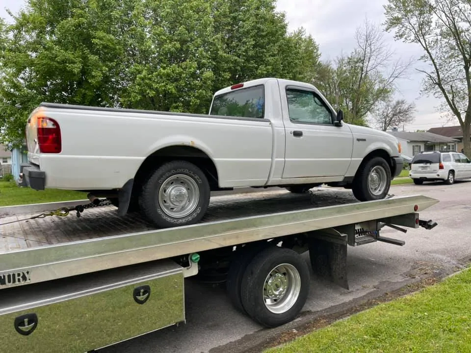 White Ford Ranger with rusted wheel arches on a tow truck, the slow rust that outpaces any scrap market rally