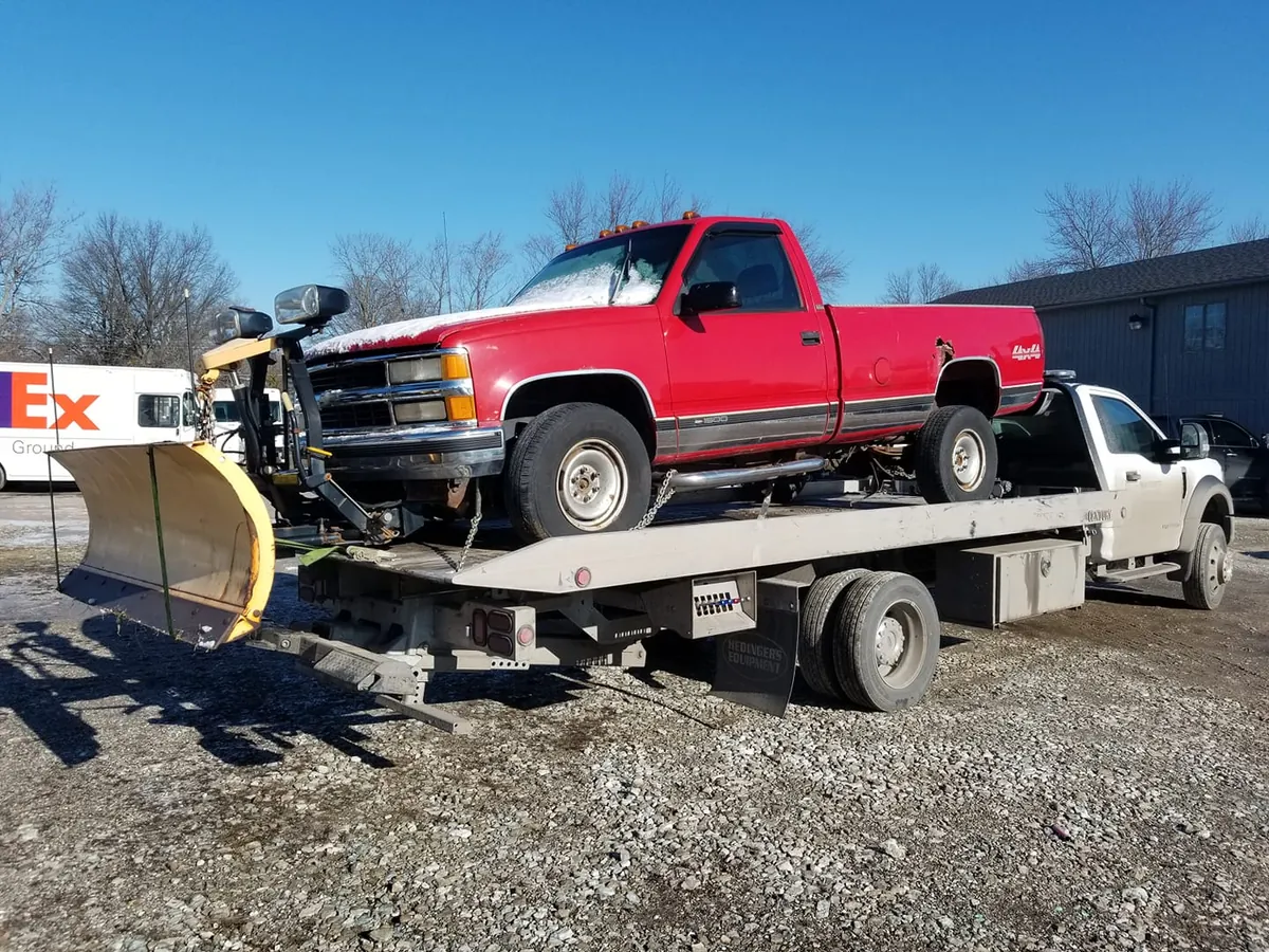 Red Chevrolet C/K 4x4 pickup with a snow plow being loaded in Indianapolis -- full-size trucks carry big, high-clearance converters