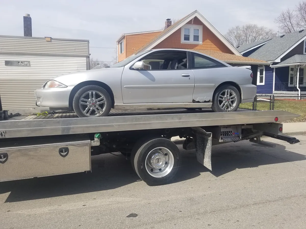 Heavily rusted early-2000s Chevrolet Cavalier on a flatbed at an Indianapolis salvage yard, the kind of scrap-bound vehicle a Certificate of Authority is written for
