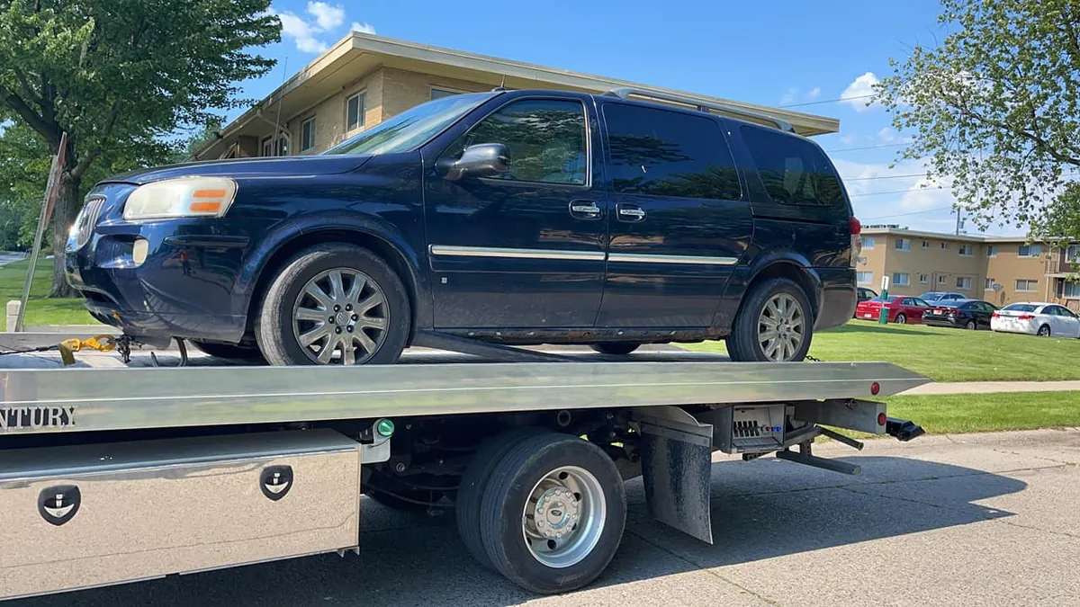 Rusted minivan on a tow truck in Indianapolis -- a legitimate buyer never deducts towing from the offer