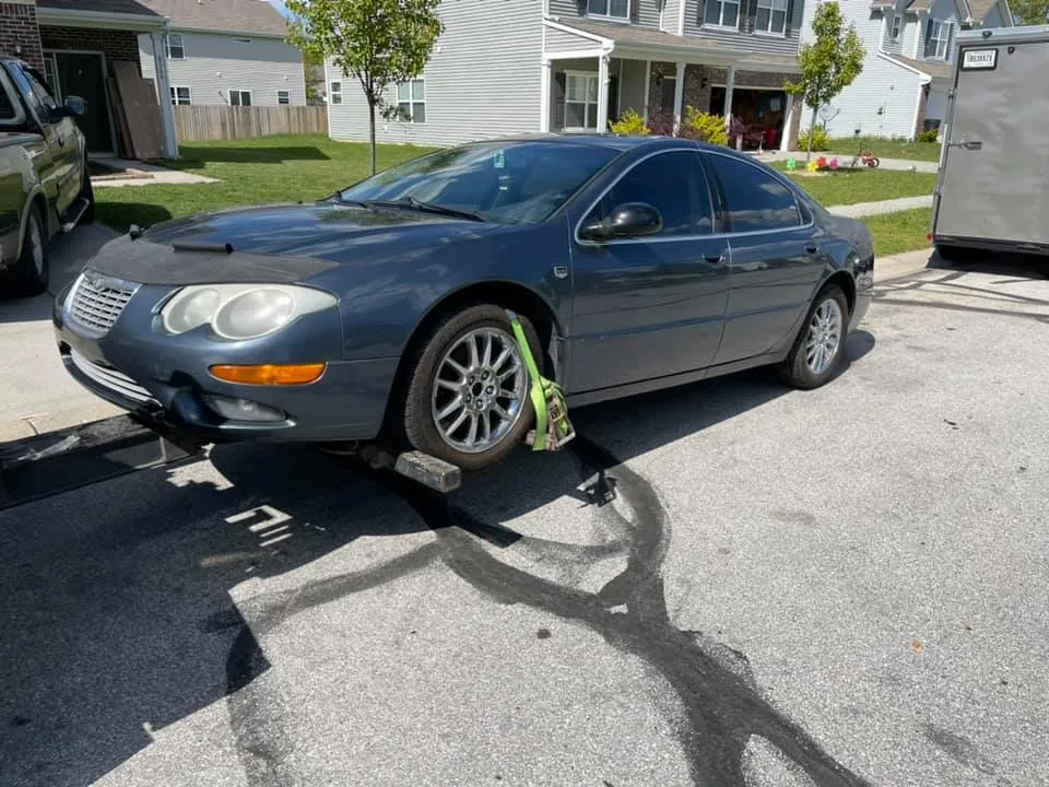 Driver securing a Chrysler 300M with wheel straps before loading -- the walk-around and load take about 15 minutes