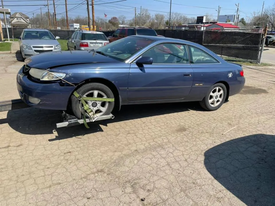 Blue Toyota Camry Solara with front-end damage on a tow dolly, an Indiana title that updates through the buyer's paperwork
