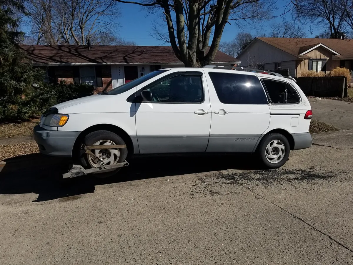 White first-generation Toyota Sienna in an Indianapolis driveway -- Toyota factory converters grade as foreign OEM, one of the better-paying scrap tiers