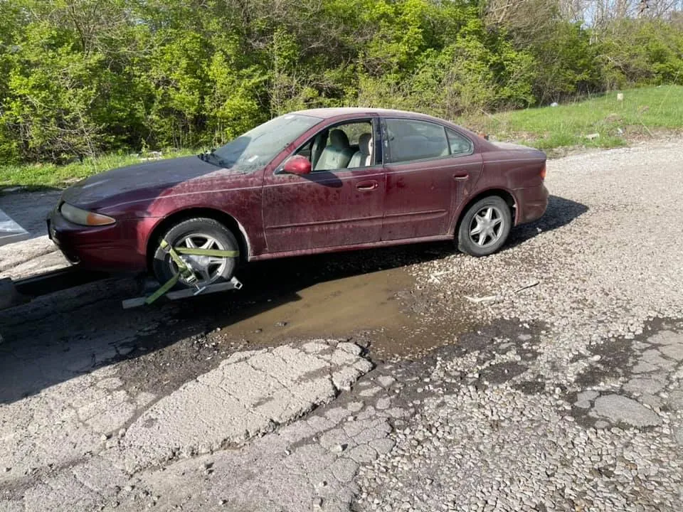 A dark red Oldsmobile Alero secured on a tow dolly -- sold for cash, picked up at home, no dealership required