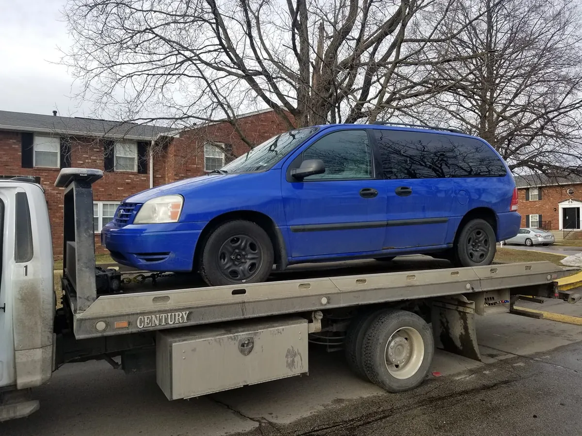 Blue Ford Freestar minivan strapped to a flatbed in Indianapolis, sold for cash at pickup instead of donated